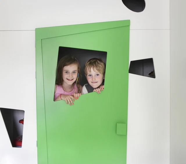 Vanessa Kilduff's children Leyla and Dillon peep out of their playhouse, made by Robert Mooney furniture. 