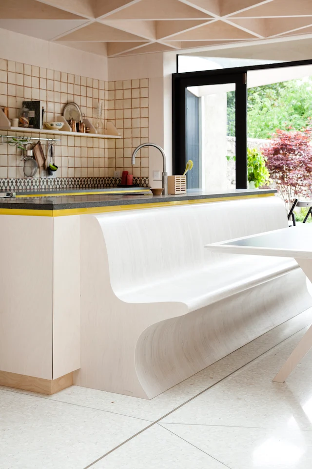 The new kitchen is anchored by Oikos cabinetry and a basalt countertop. A Fired Earth tile backsplash pops against its ply surroundings, while the island features a Franke sink and Quooker tap.