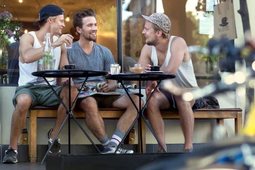 Three young men sitting outside cafe