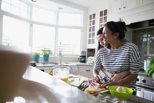 Mother and daughter hugging and cooking in kitchen