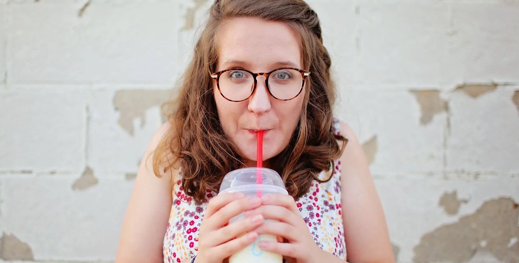 Woman sipping through plastic straw, ahead of ban