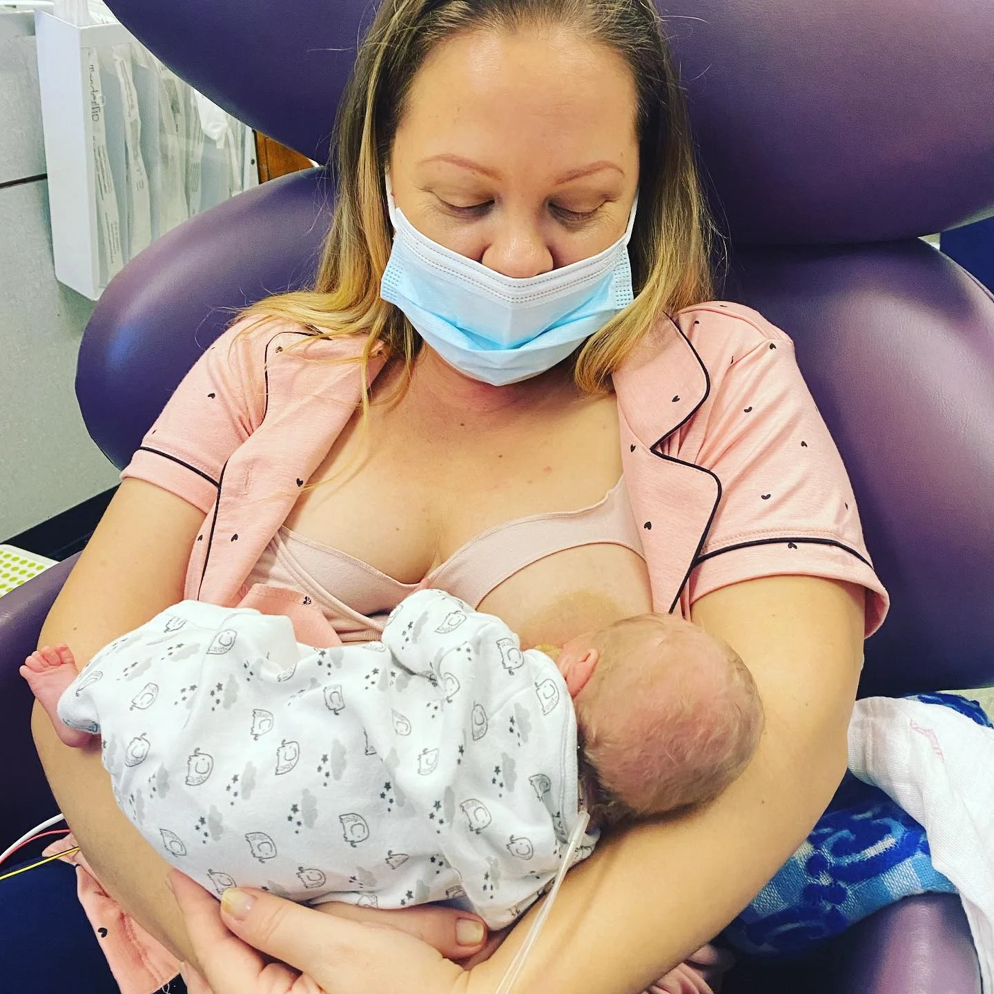 woman holding newborn baby and breastfeeding in a hospital chair