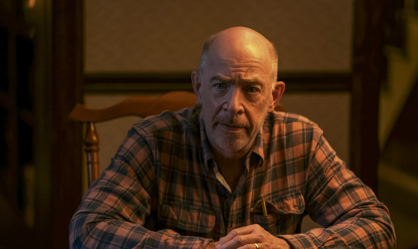 man wearing plaid shirt with hands on table