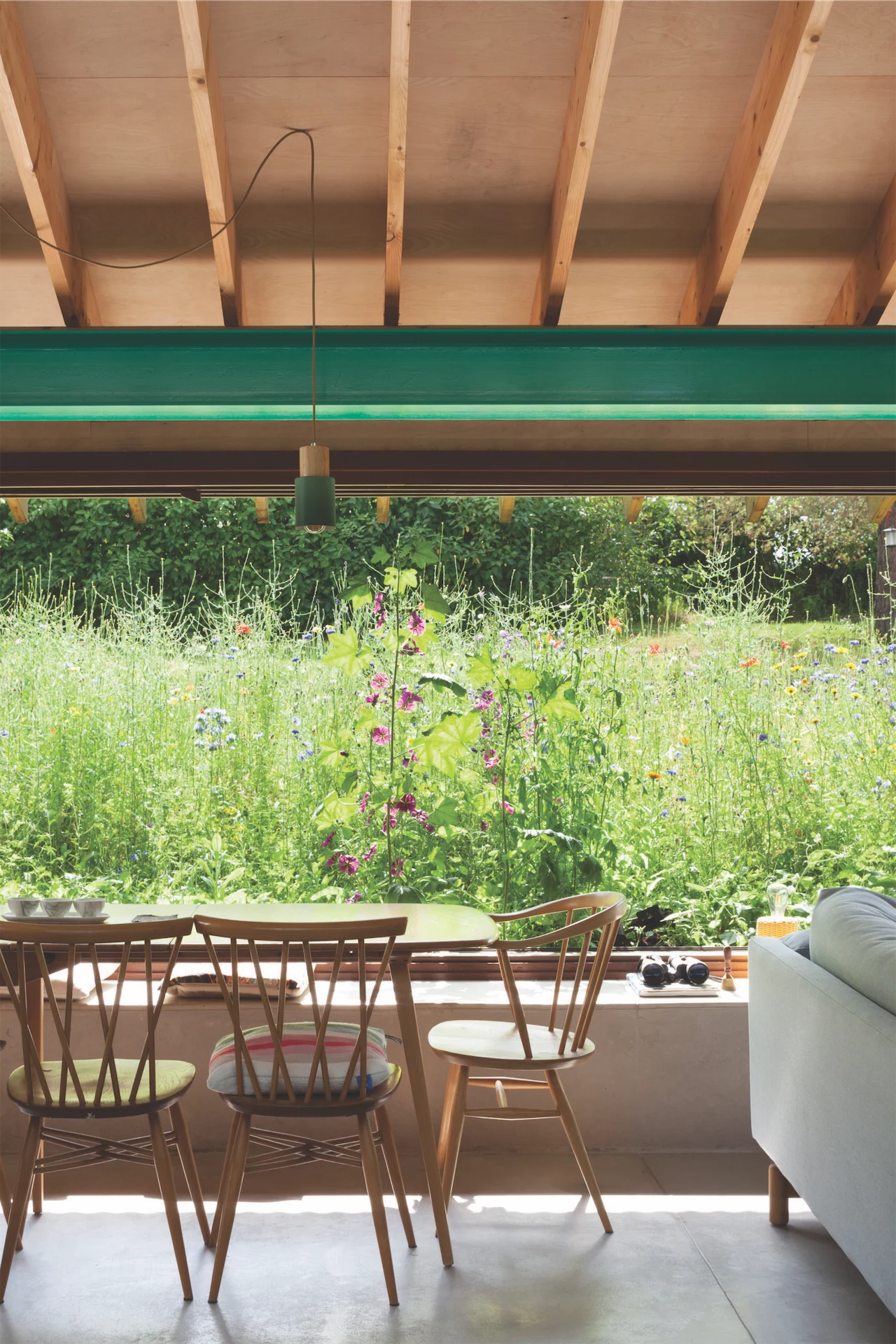 The main living space features an 8m-wide landscape window looking out to the wildflower meadow. 