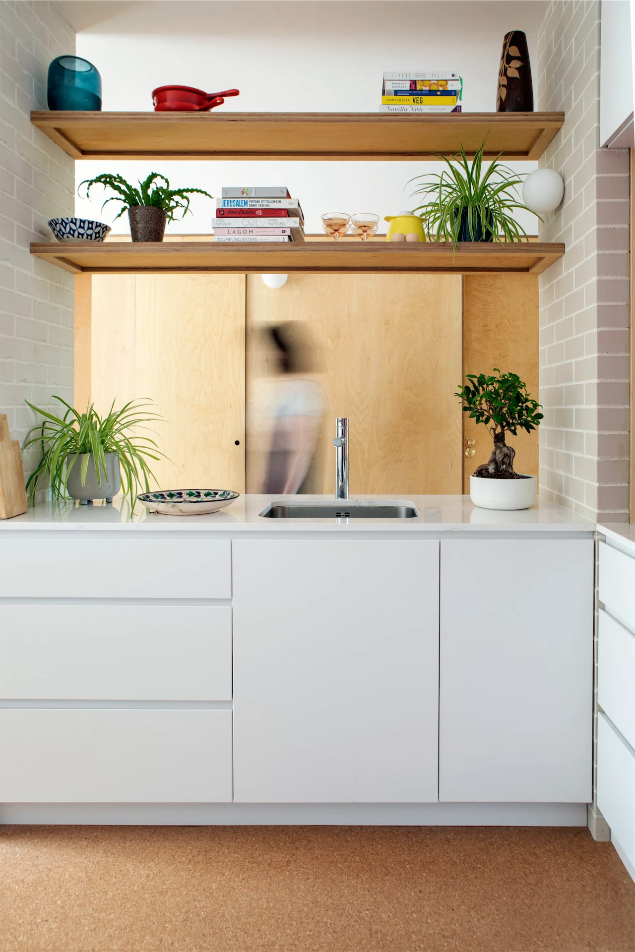 A plaster wall was taken down to create this worktop and sink area, with open shelving above. “It still works to divide the room, but it doesn’t feel so closed in.” 