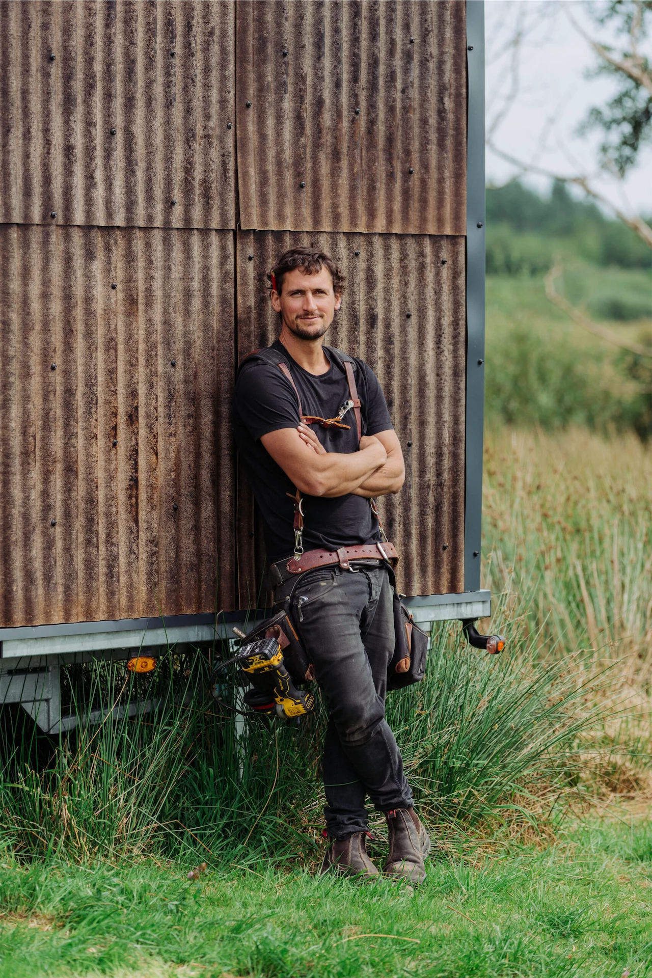 Harrison leaning on a Tigín clad in eco-friendly, hemp-fibre corrugated panels sourced from Margent Farm in the UK.